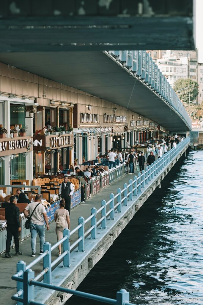 a group of people standing on a pier next to a body of water