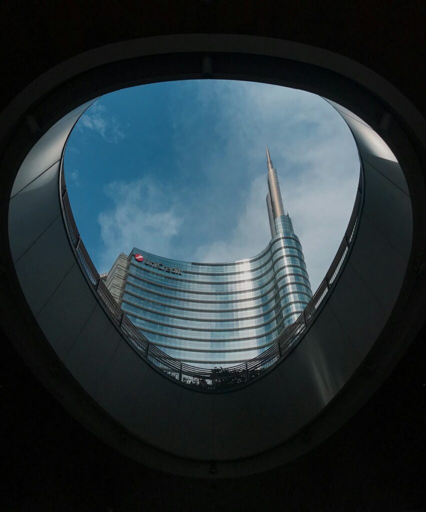 worms eye view of gray concrete building under blue and white sunny cloudy sky during