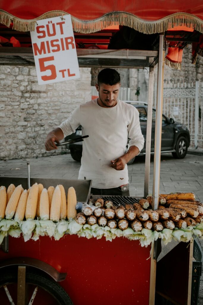 a man cooking food on a grill in front of a red cart